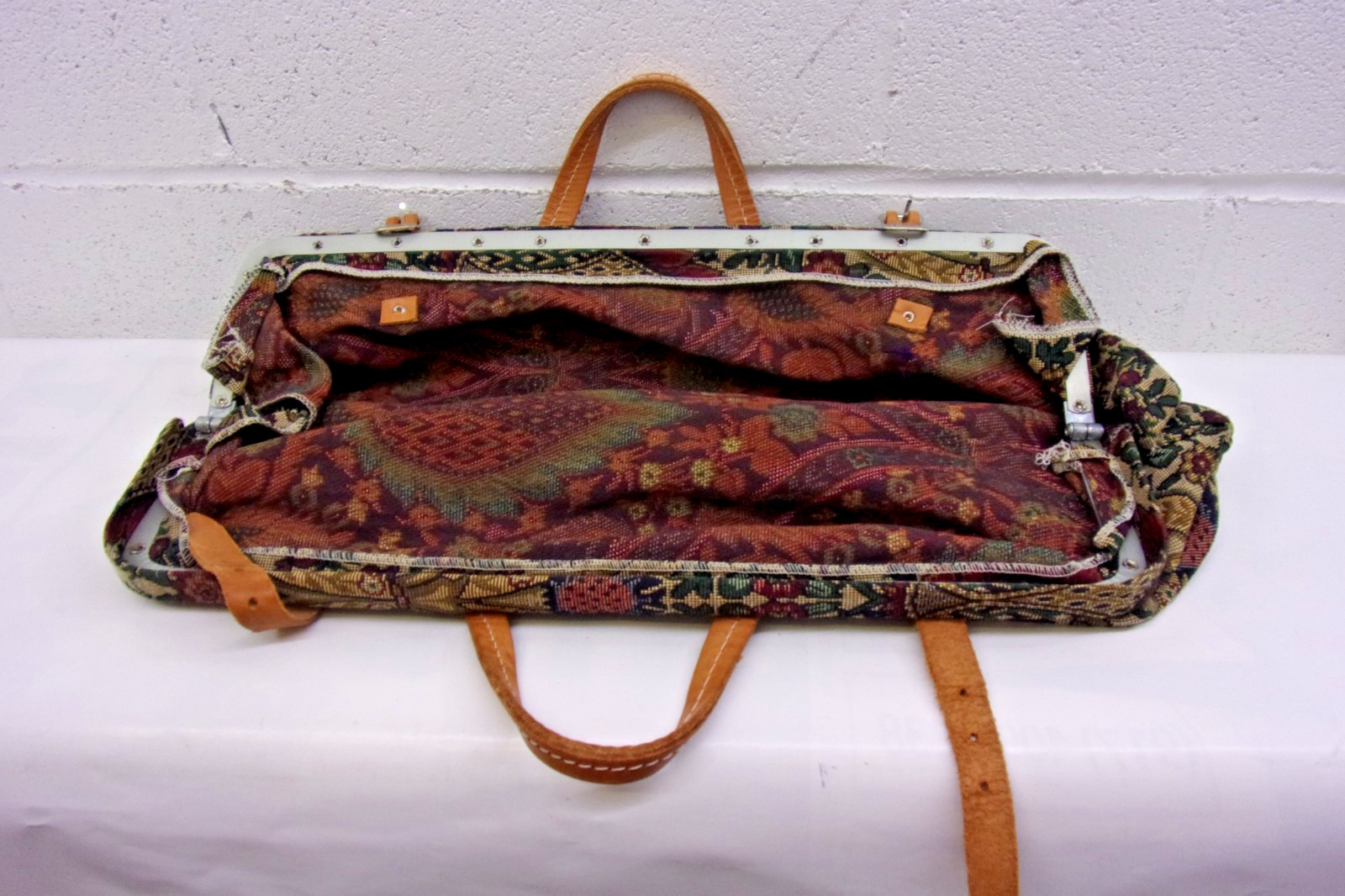 Victorian-era tapestry travel bag with leather handles and metal frame