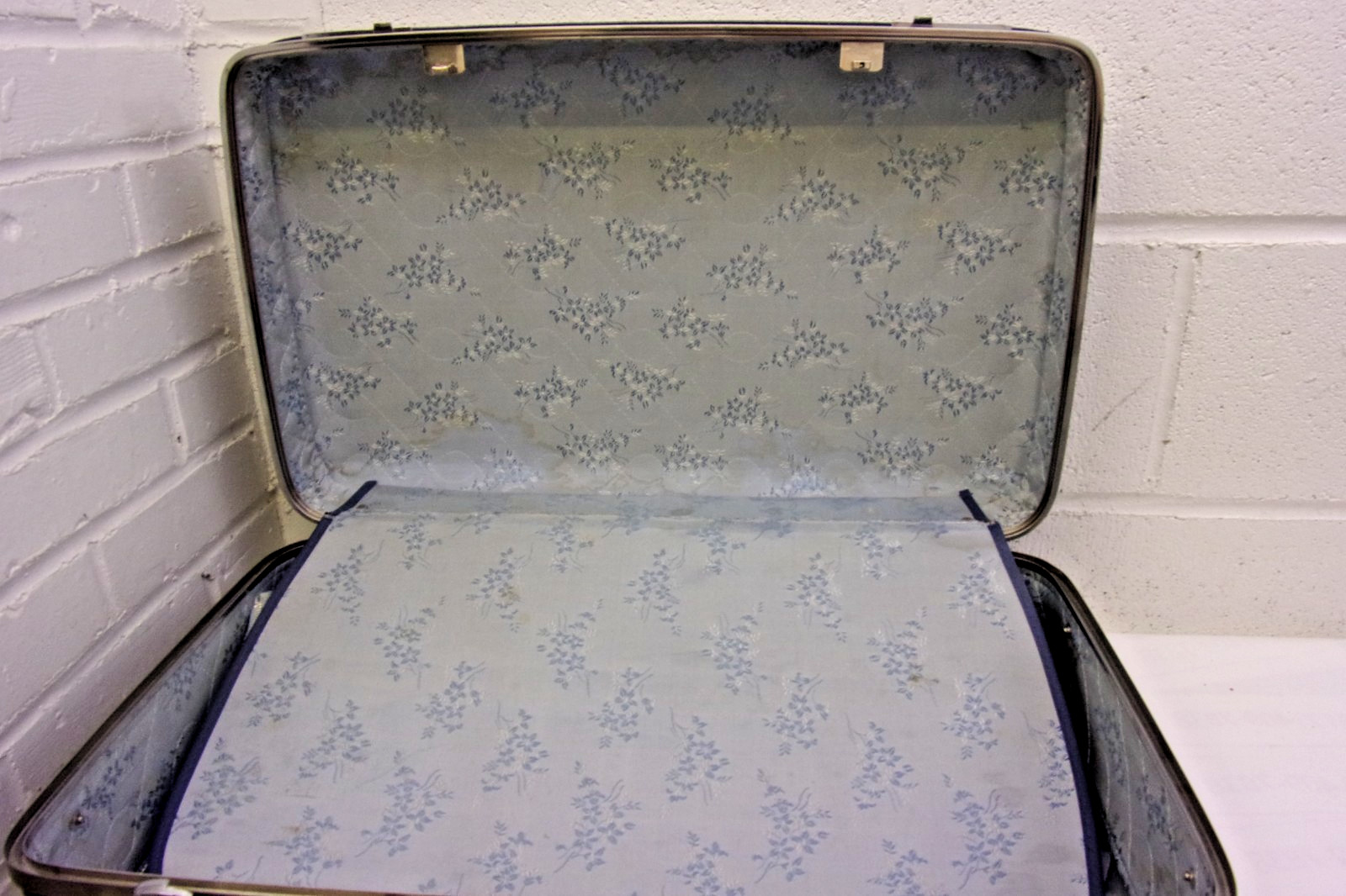Vintage American Tourister hard-shell blue suitcase with chrome accents.