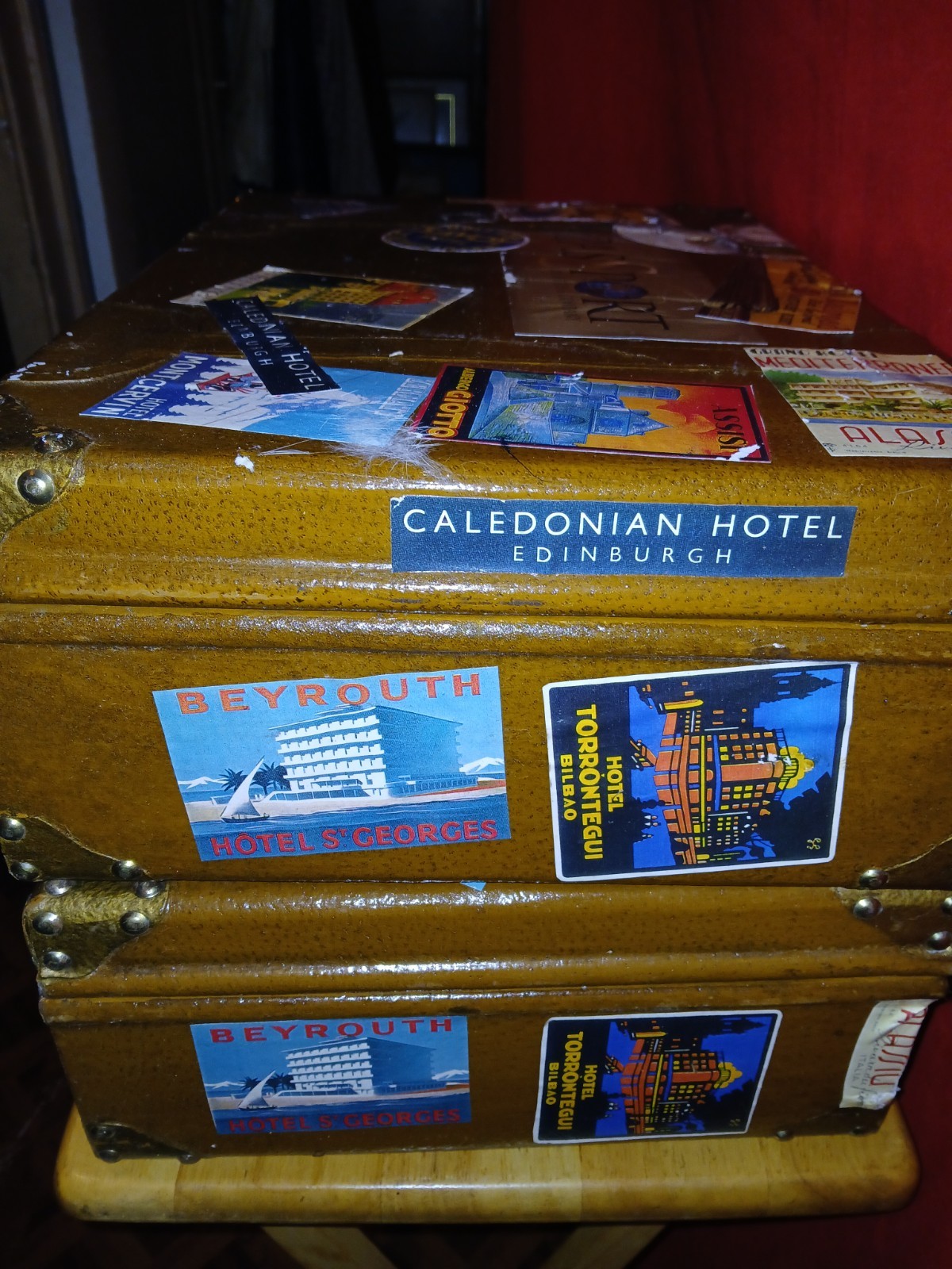 Set Of 4 Vintage Traveling Suitcases By “Keith ” with brown wooden trunk.